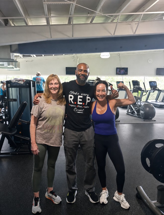 Tim standing with two clients after training at the gym